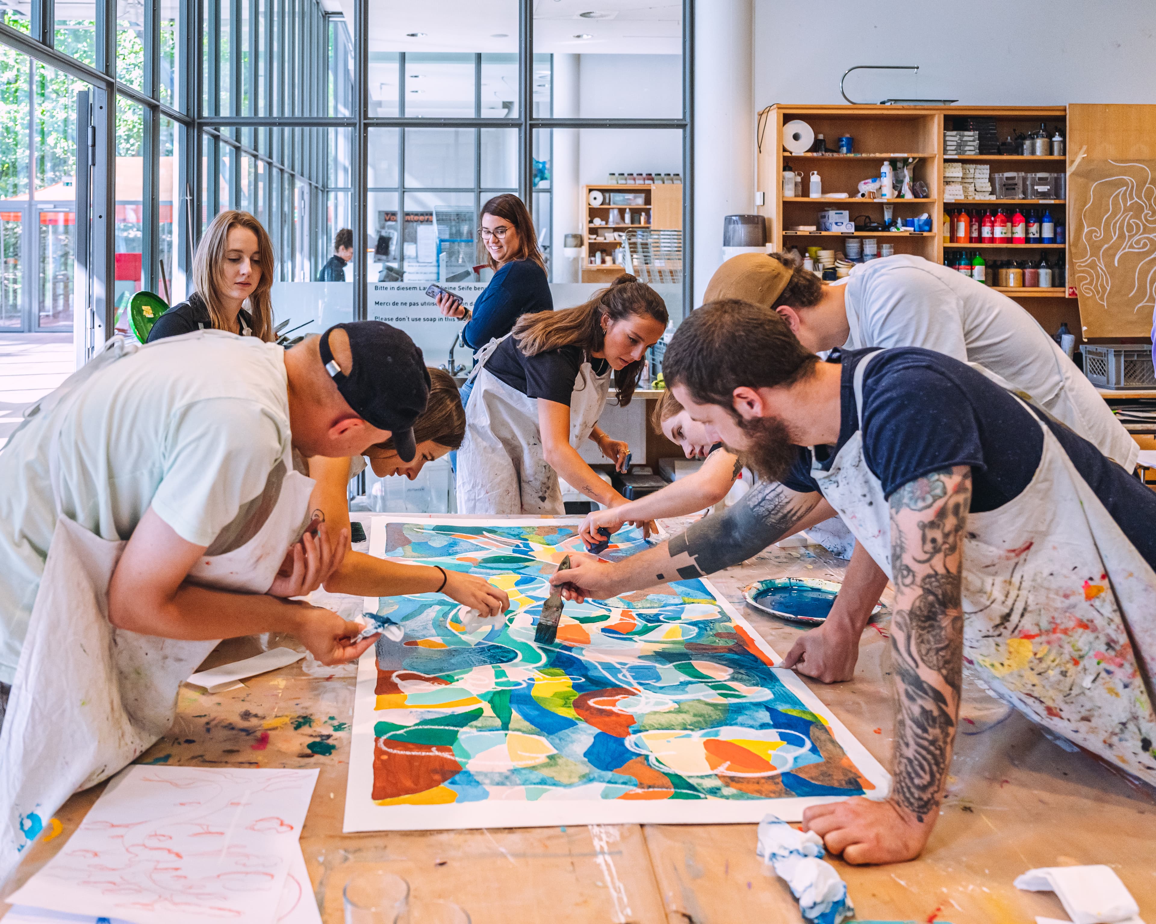 Während eines Workshops für Teams und Unternehmen gestalten mehrere Menschen gleichzeitig an einem Gemeinschaftswerk im Atelier