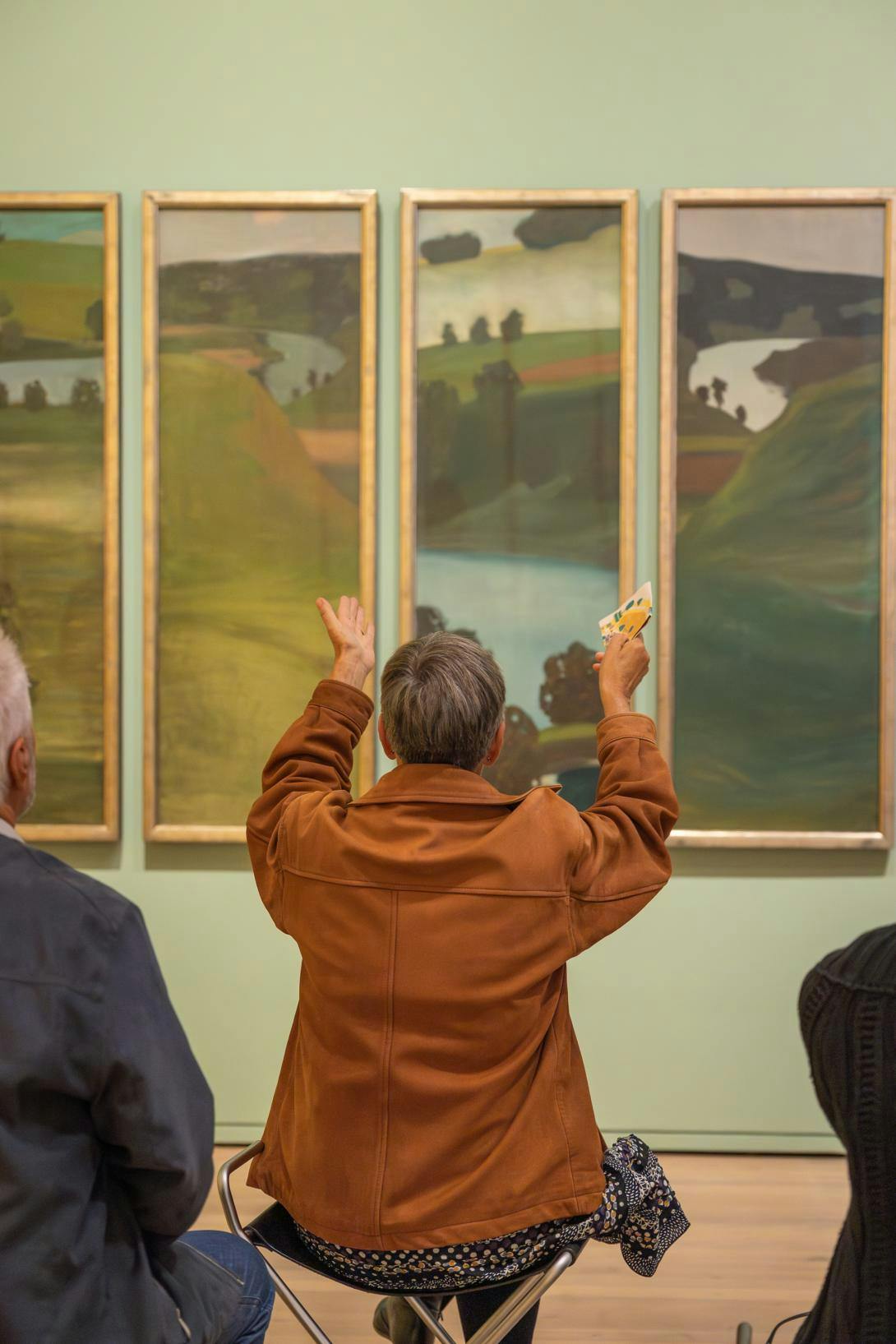 Person von hinten vor einem Werk Paul Klees, inmitten anderer Personen, zum Bild hin gestikulierend. 