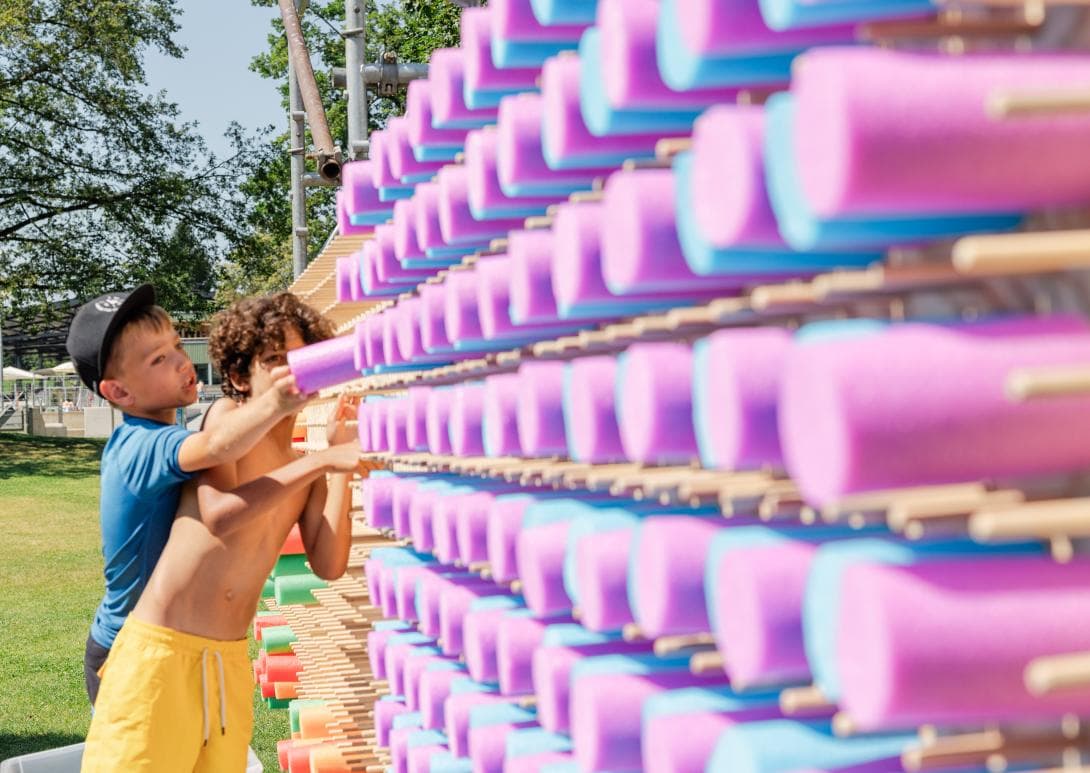 Zwei Jungen prüfen ihr Werk an der Schwimmnudel-Steckwand, die sie komplett in violett und blau gestaltet haben.