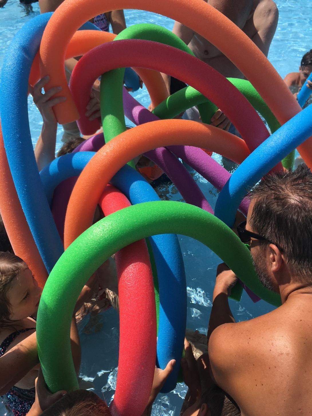 Skulptur aus Schwimmnudeln, die von vielen Menschen zusammengehalten wird.