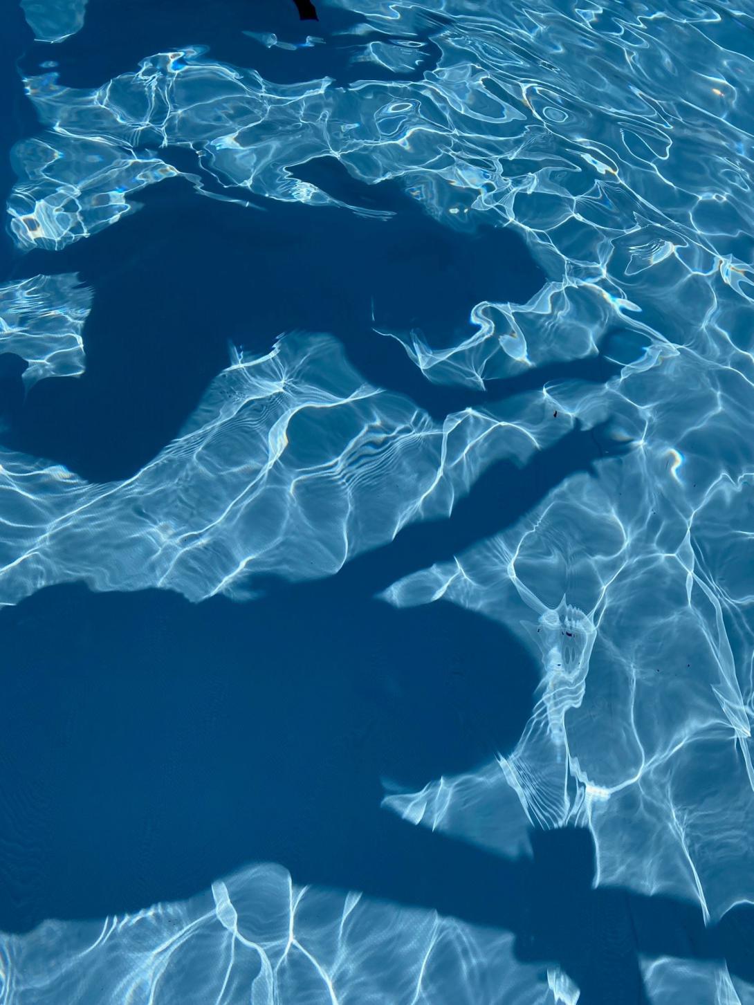 Schatten von tanzenden Menschen im Wasser