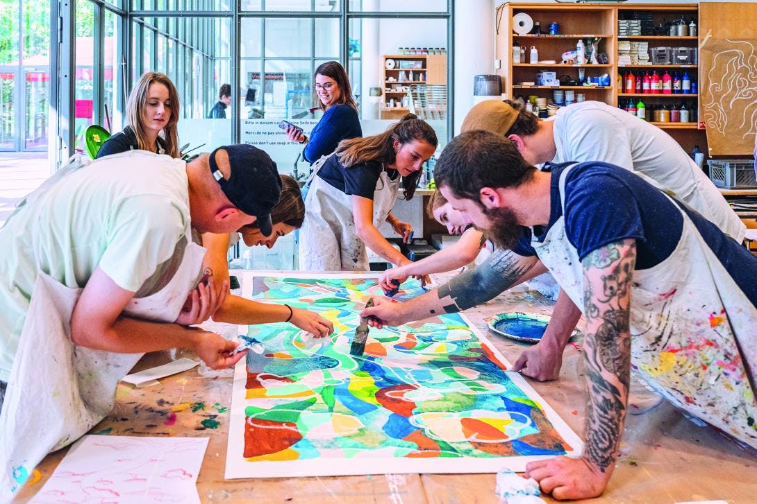 Ein Team aus unterschiedlichen Menschen gestaltet gemeinsam ein Kunstwerk im Atelier