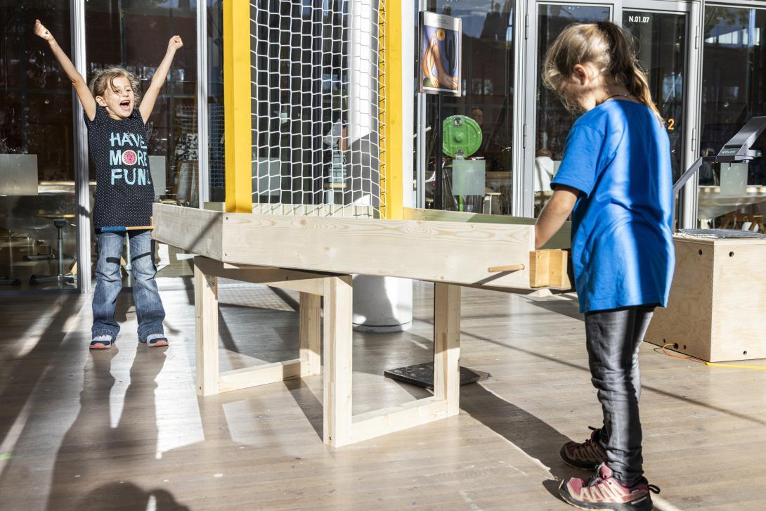 Zwei Mädchen spielen eine Art Tischfussball, eine wirft die Arme in die Höhe