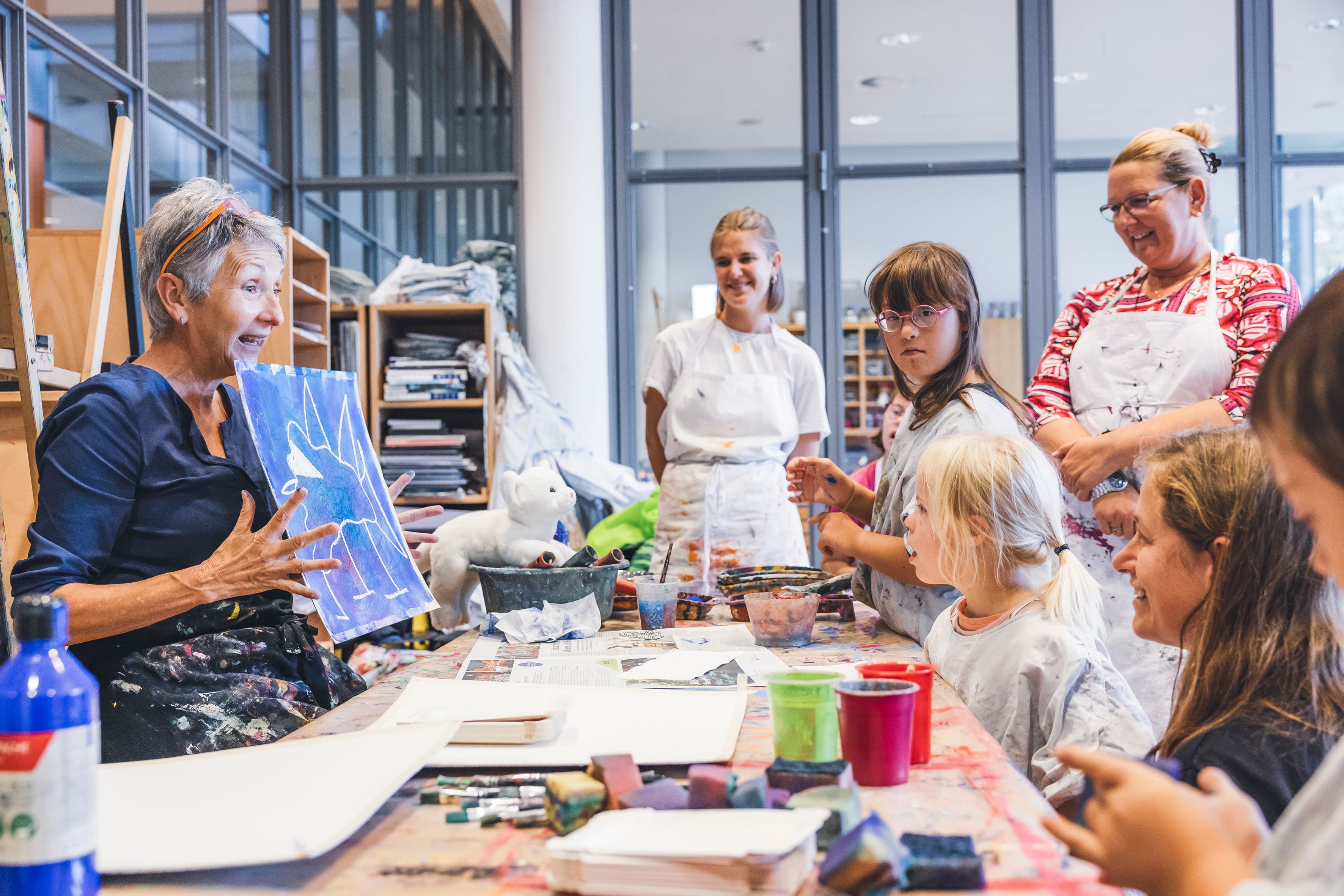 Kunstvermittlerin Verena Wyss zeigt Kindern und Erwachsenen ein Beispielwerk im Atelier