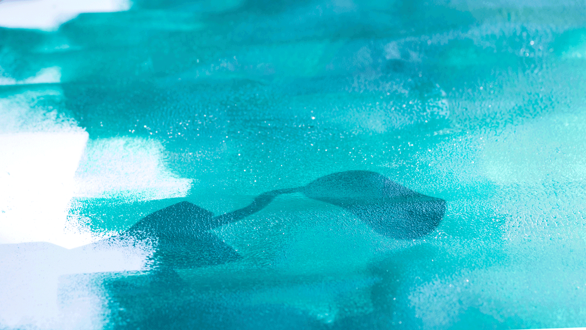 Türkisfarbe ist auf einem weissen Malgrund mit einer Rolle aufgetragen. Im unteren Bildteil befindet sich der Schatten der Rolle.